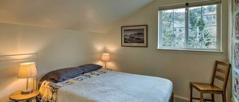 A bedroom with a bed, a chair, a lamp, a window, and a picture on the wall.