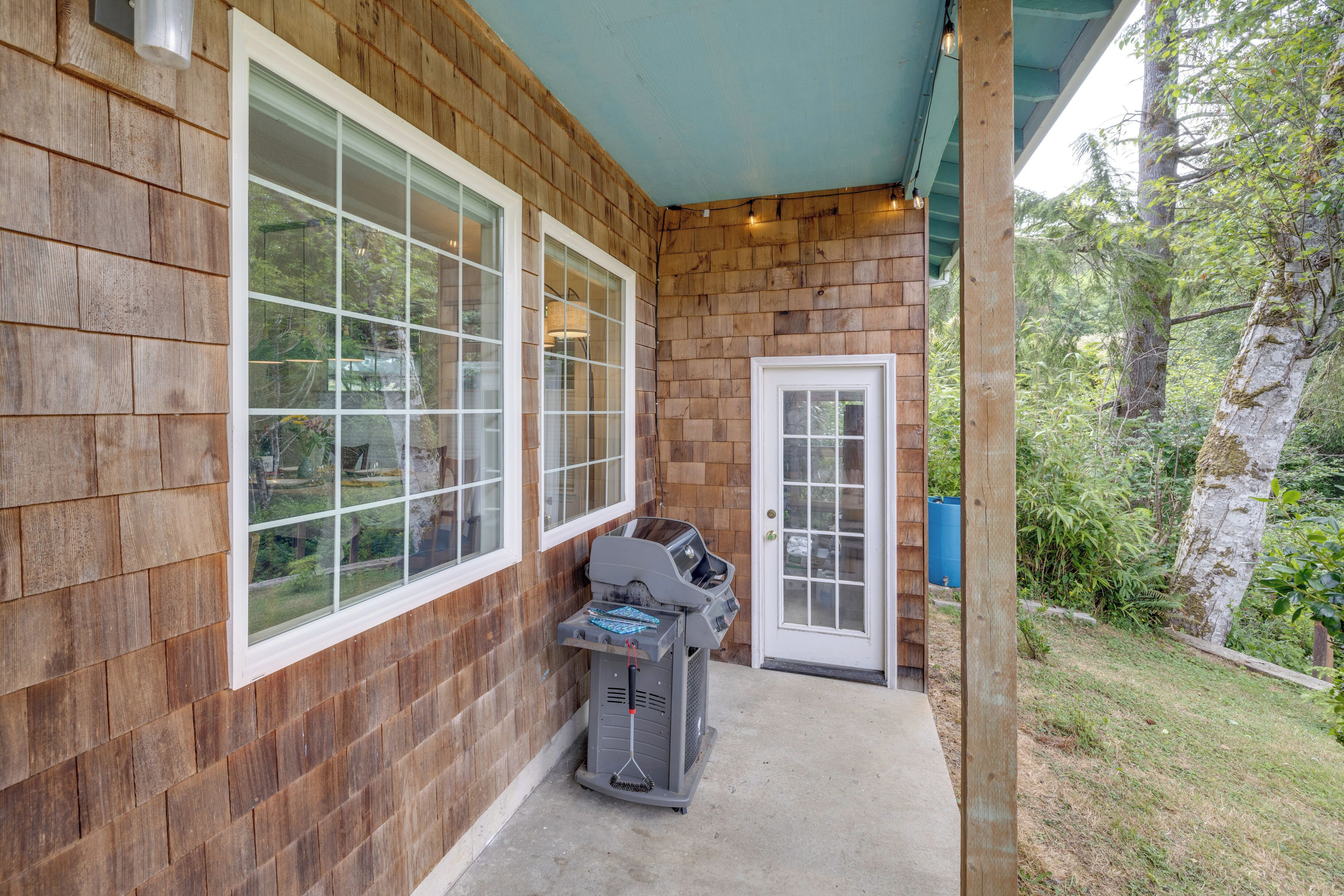 A wooden exterior with a covered porch, a grill, and a door.