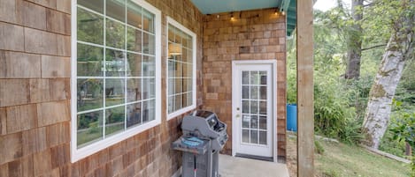 A wooden exterior with a covered porch, a grill, and a door.