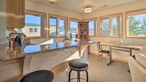 A kitchen with a central island, bar stools, a dining table, and a red cabinet. - Charming Studio - 3 Miles From Kolob Canyons! (New Harmony)