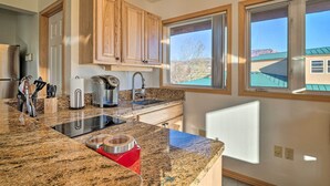 A kitchen with granite countertops, wooden cabinets, a built-in oven, and a window with a view of a mountain. - Charming Studio - 3 Miles From Kolob Canyons! (New Harmony)
