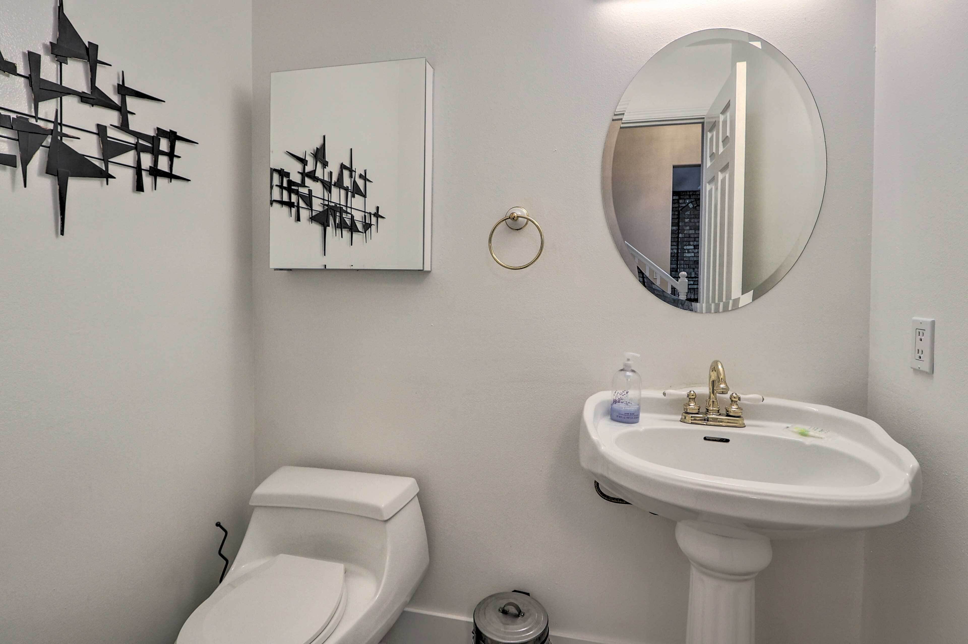 A bathroom with a toilet, sink, and mirror.