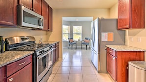 A kitchen with wooden cabinets, stainless steel appliances, granite countertops, and a dining area with chairs. - Spacious Conroe Home - 6 Mi to The Woodlands! (Conroe)