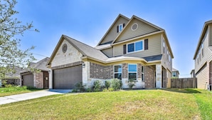 A two-story house with a garage, a brick facade, and a well-maintained lawn. - Spacious Conroe Home - 6 Mi to The Woodlands! (Conroe)