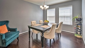 A dining area with a dark wooden table, beige upholstered chairs, a teal armchair, and a chandelier. - Spacious Conroe Home - 6 Mi to The Woodlands! (Conroe)