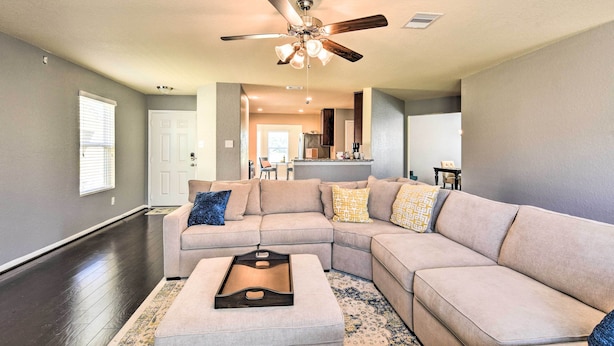 A spacious living room with a large sectional sofa, a ceiling fan, and a kitchen area in the background. - Spacious Conroe Home - 6 Mi to The Woodlands! (Conroe)