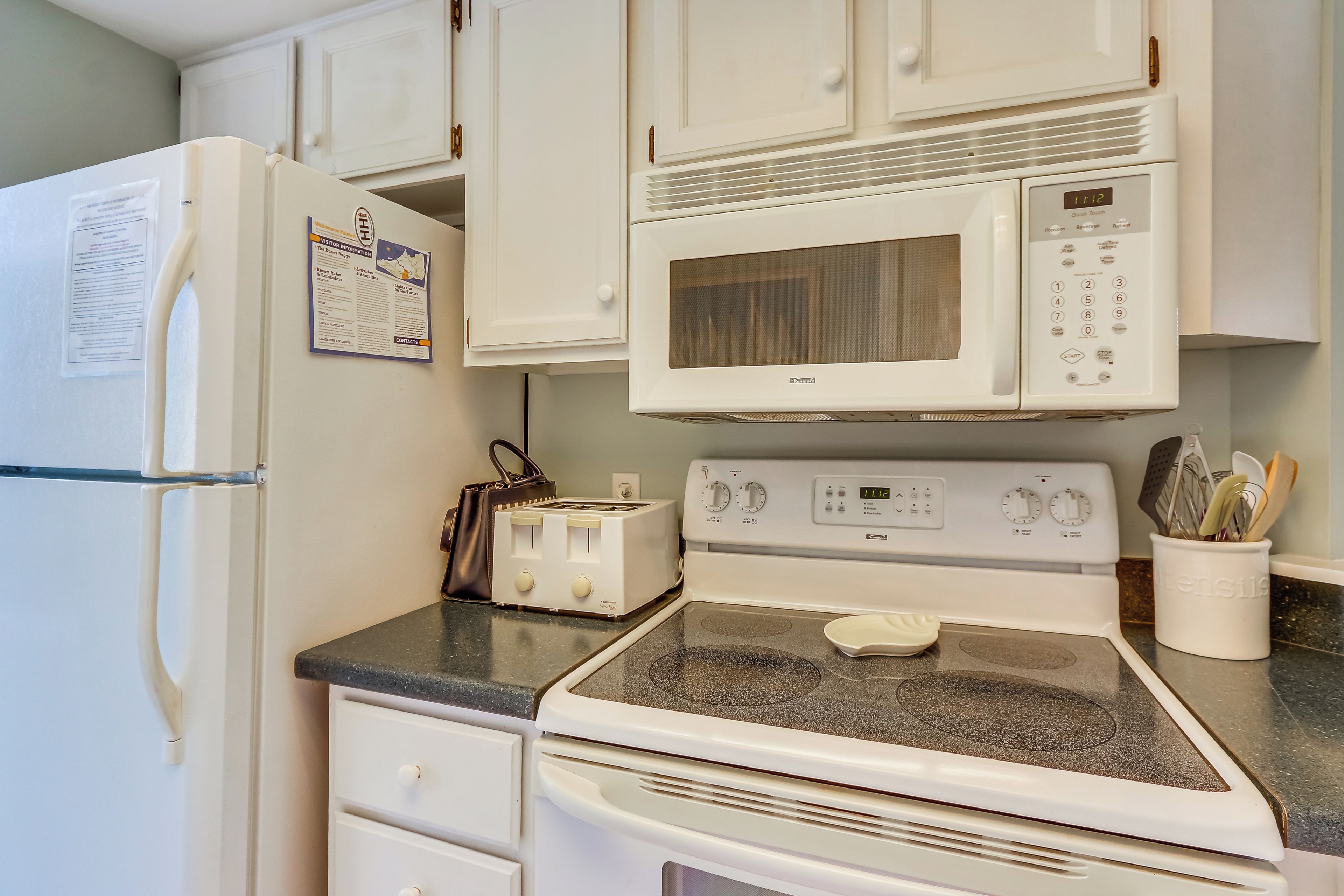 A kitchen with a white refrigerator, a microwave, a stove, and a toaster.