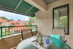 A balcony with a glass table, chairs, a lantern, and a view of buildings. - 2 Mi to Beach! Hilton Head Golf Escape w/ Balcony (Hilton Head Island)