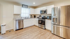 Una cocina moderna con gabinetes blancos, electrodomésticos de acero inoxidable y suelo de madera.