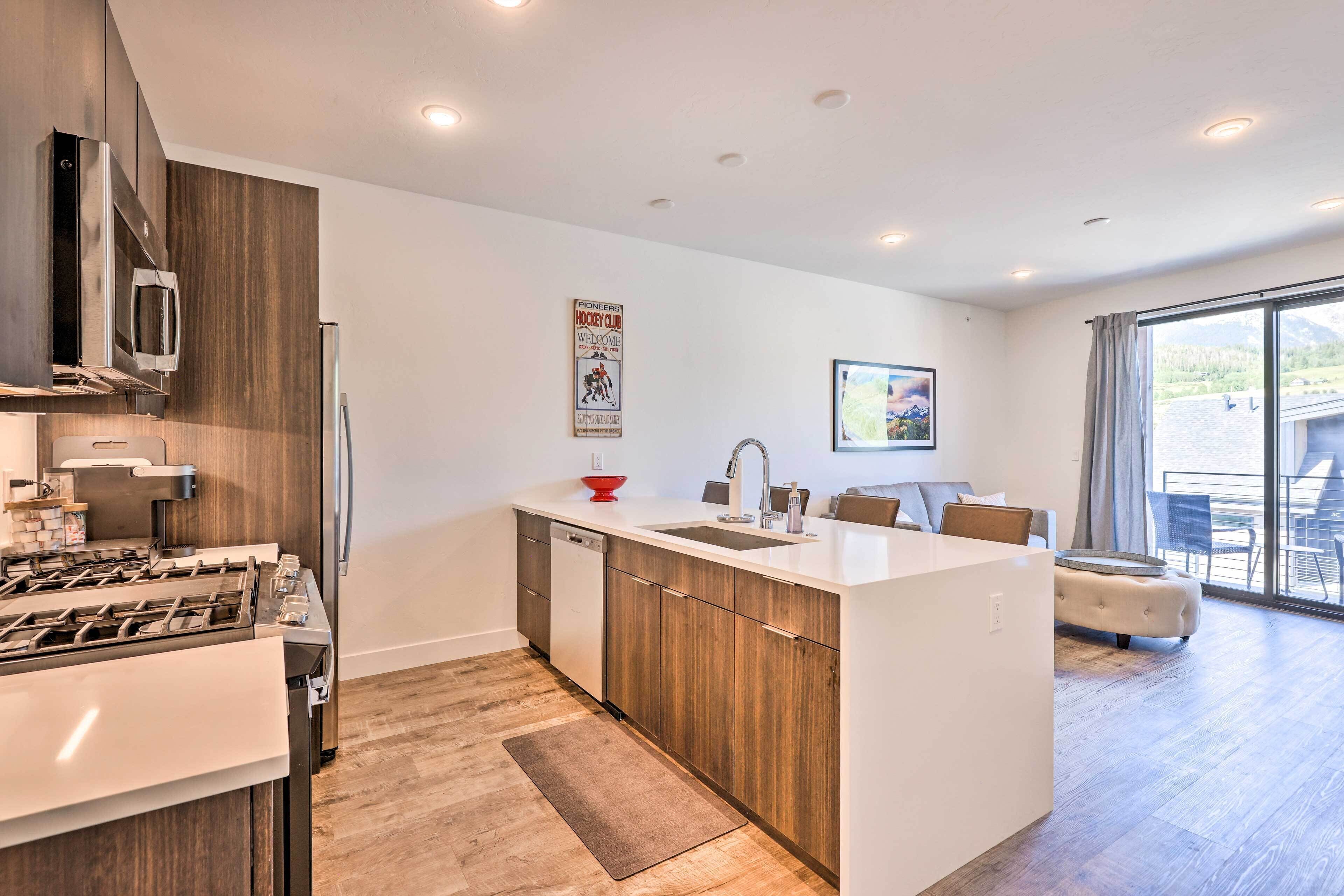 A modern kitchen with a central island, stainless steel appliances, and a dining area with a view.