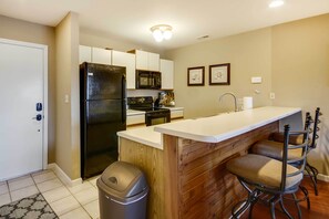 A compact kitchen with a refrigerator, microwave, and stove. There is a wooden island with bar stools. - 3 Pools! Lake-view Family Condo in Osage Beach (Osage Beach)