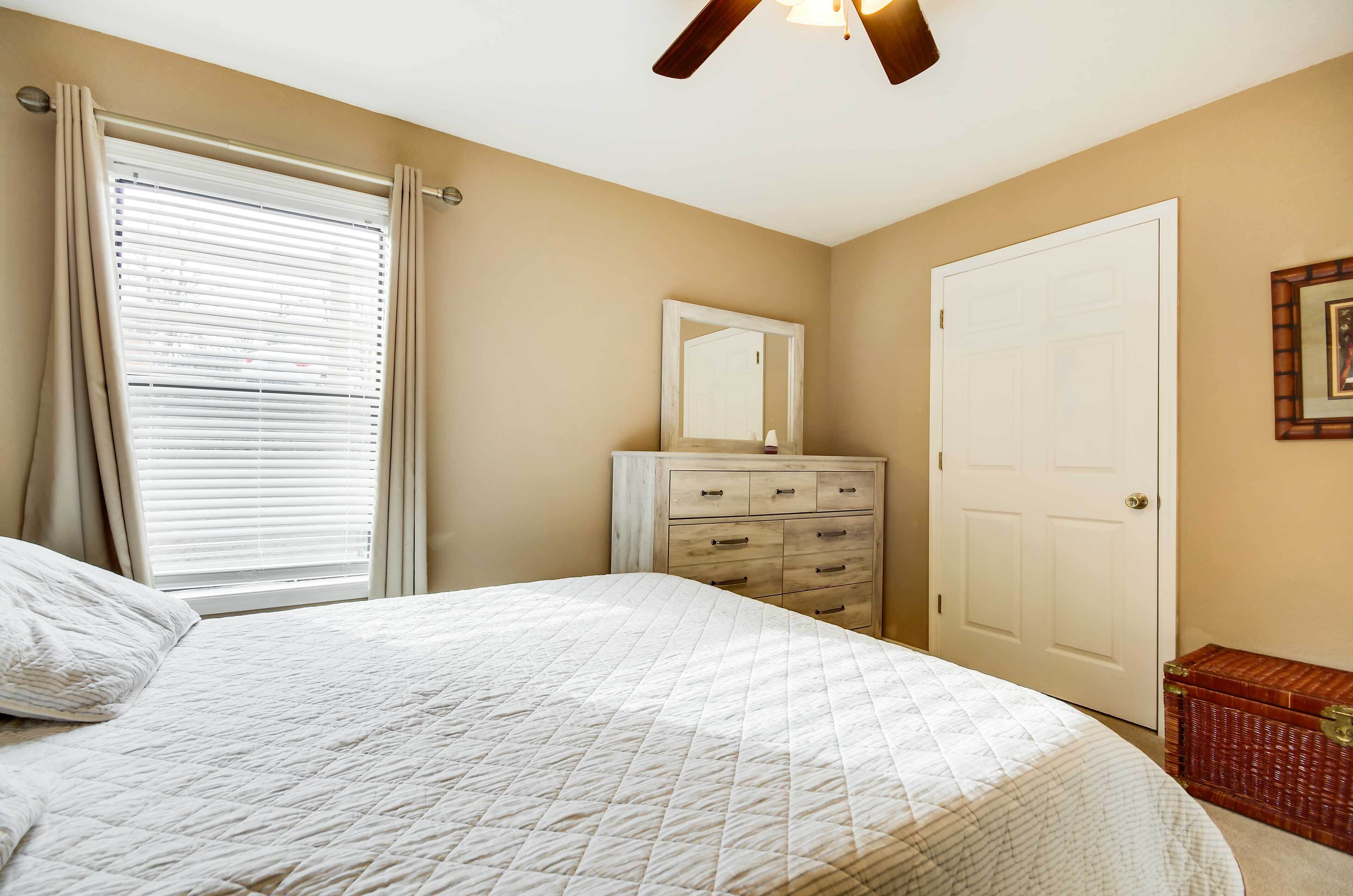 Une chambre à coucher avec un lit, une commode, un miroir et une porte.