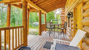 A wooden deck with a table and chairs, surrounded by log cabin walls and a wooden railing. - Access to Rocky Mtn Nat'l Park: Grand Lake Cabin (Grand Lake)
