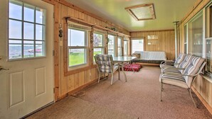 Ein Zimmer mit großen Fenstern, Holzvertäfelung, einem Tisch mit Stühlen und einem Sofa.