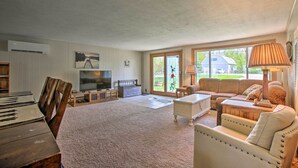 Ein geräumiges Wohnzimmer mit Klavier, Fernseher, einer Couch und einem Couchtisch.