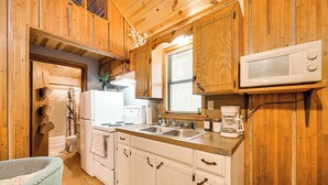 A wooden cabin-style kitchen with white cabinets, a microwave, a sink, and a coffee maker. - Rustic Cabin w/ Hot Tub Near Broken Bow Lake! (Broken Bow)