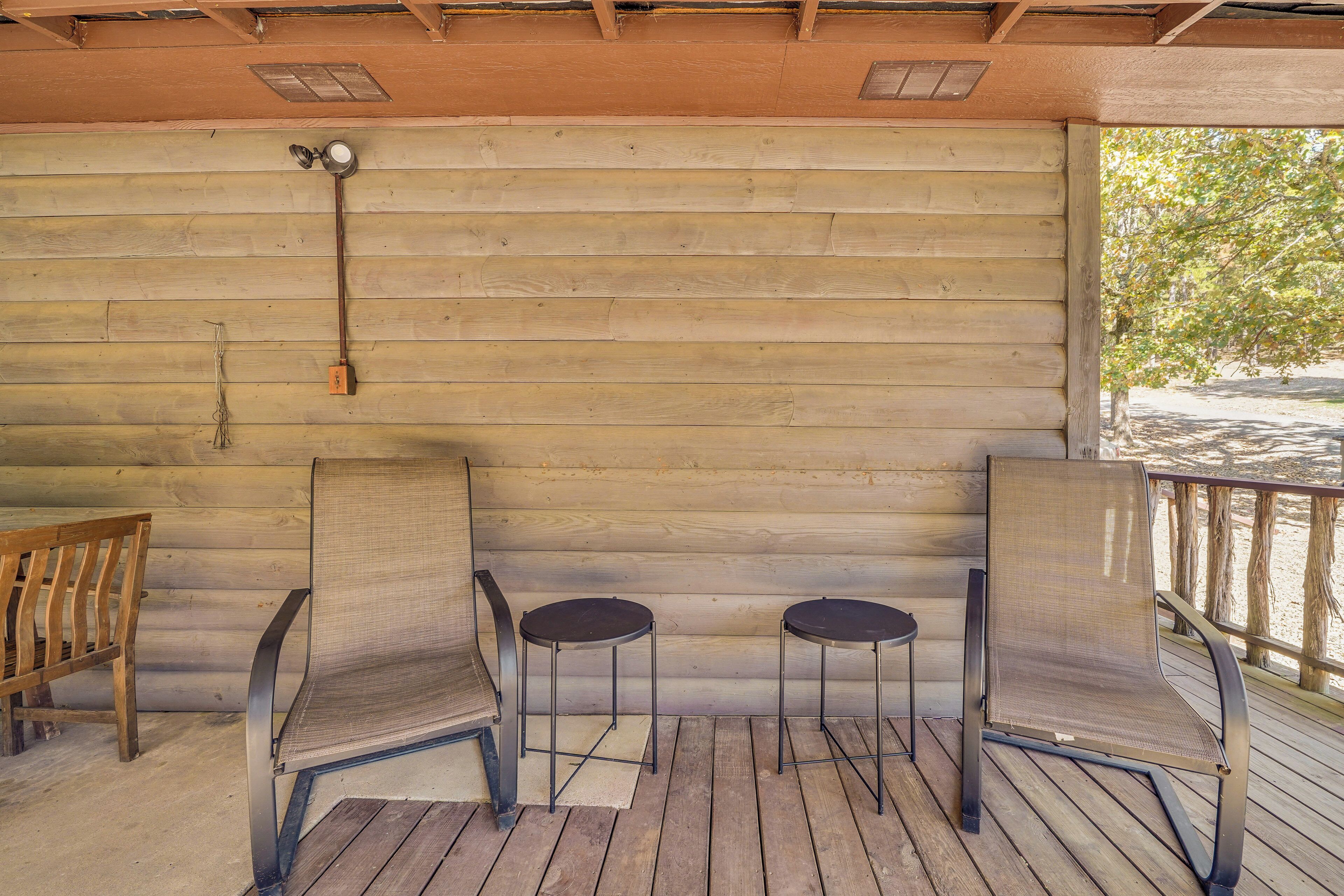 Una terraza de madera con dos sillas de metal y un banco.