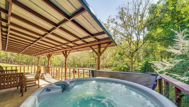 A hot tub under a wooden pergola with a view of a forested area. - Rustic Cabin w/ Hot Tub Near Broken Bow Lake! (Broken Bow)