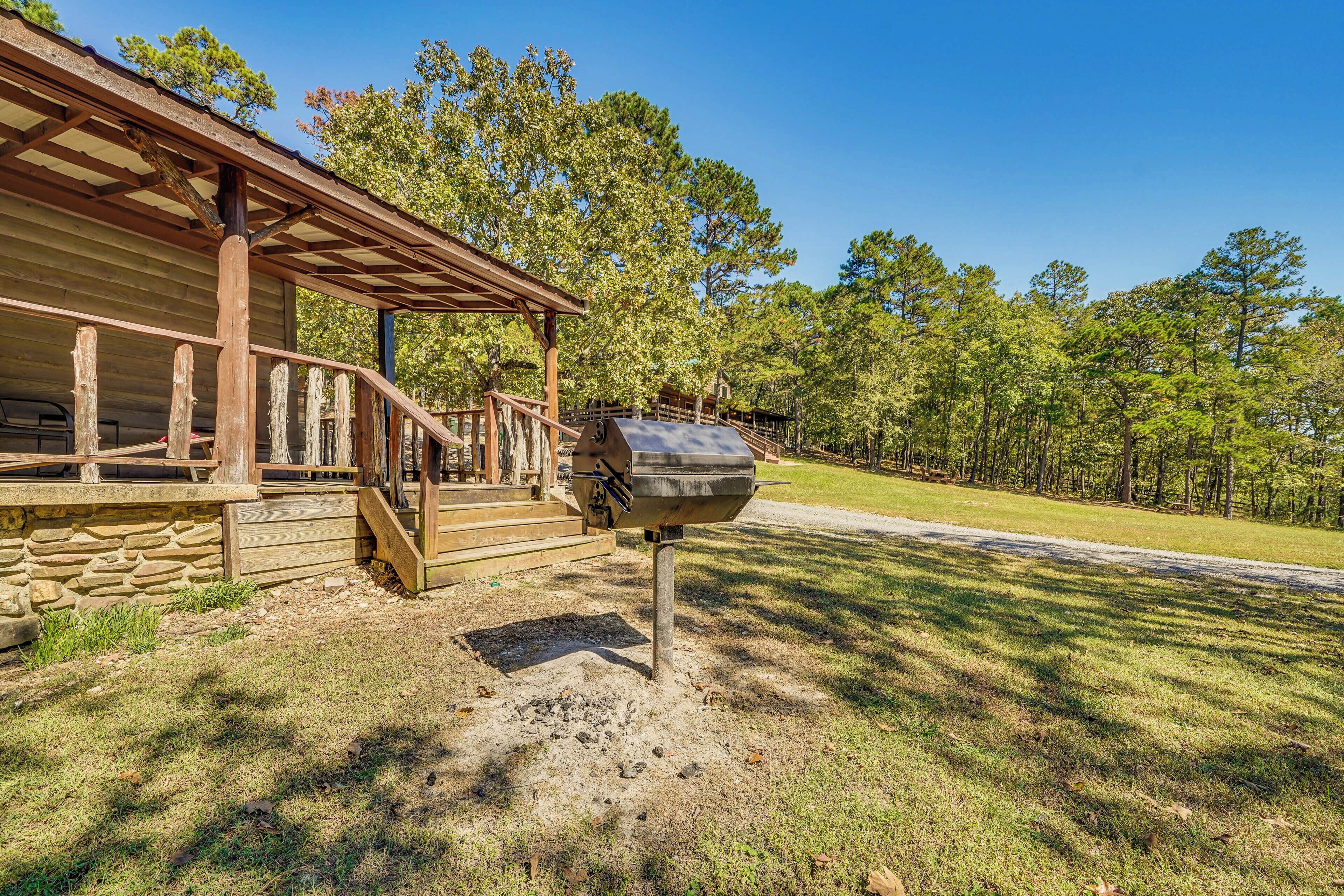 A rustic cabin with a covered porch and a grill area.