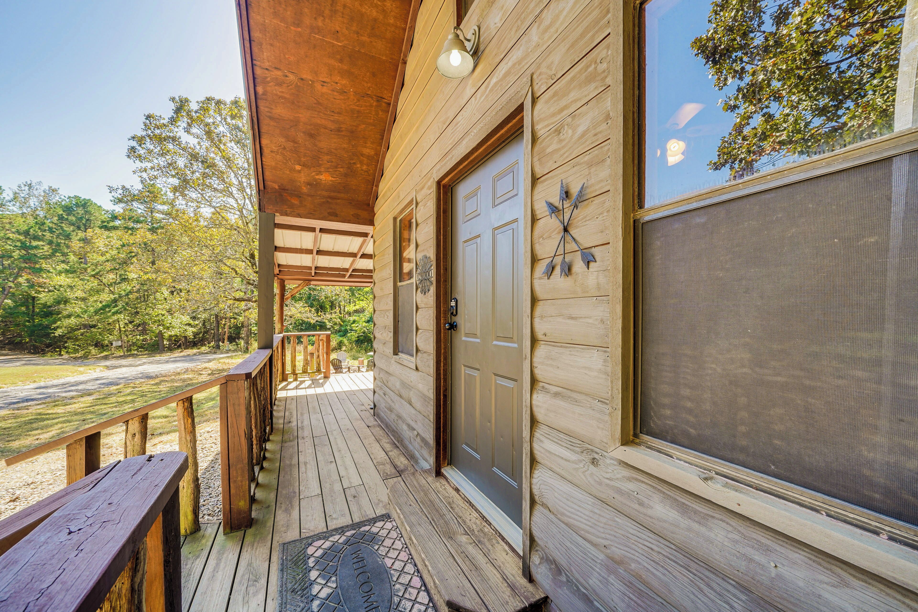 A wooden cabin with a porch, a door, and a window with a screen.