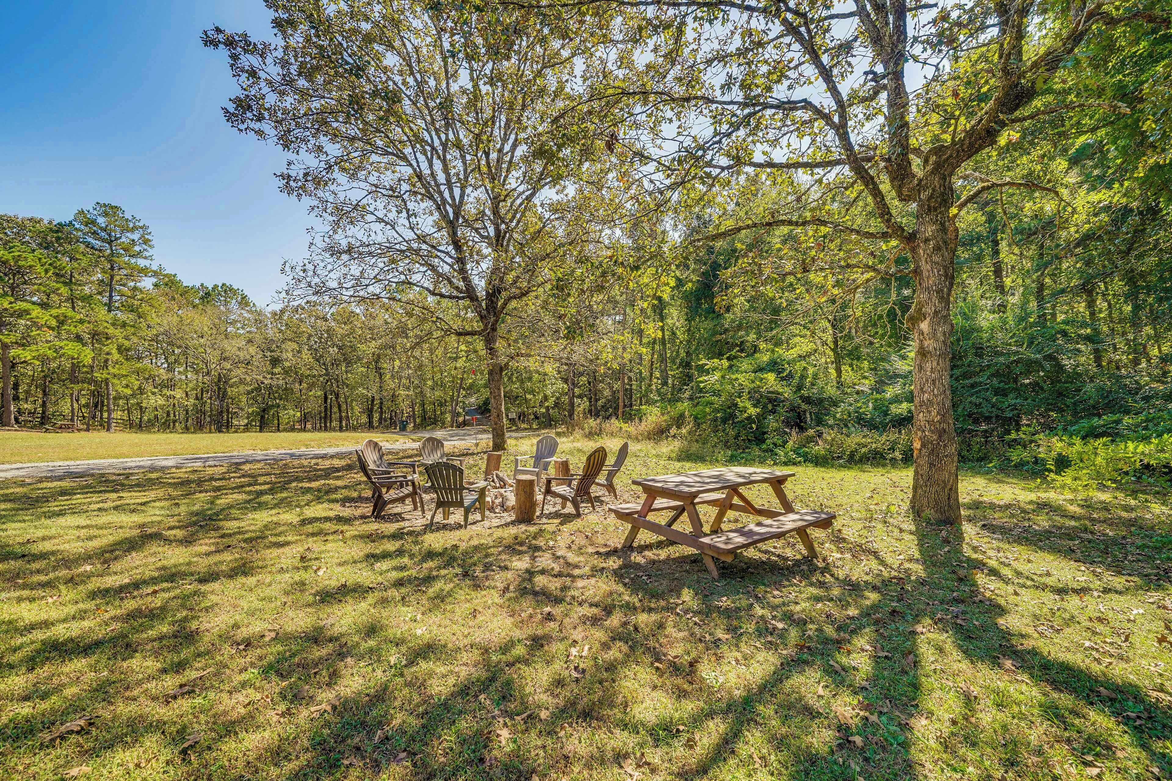 A picnic area with tables and chairs, surrounded by trees and grass.