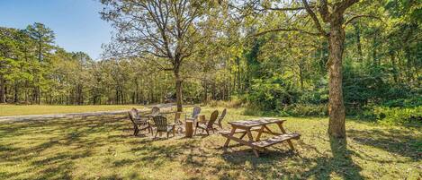 A picnic area with tables and chairs, surrounded by trees and grass.