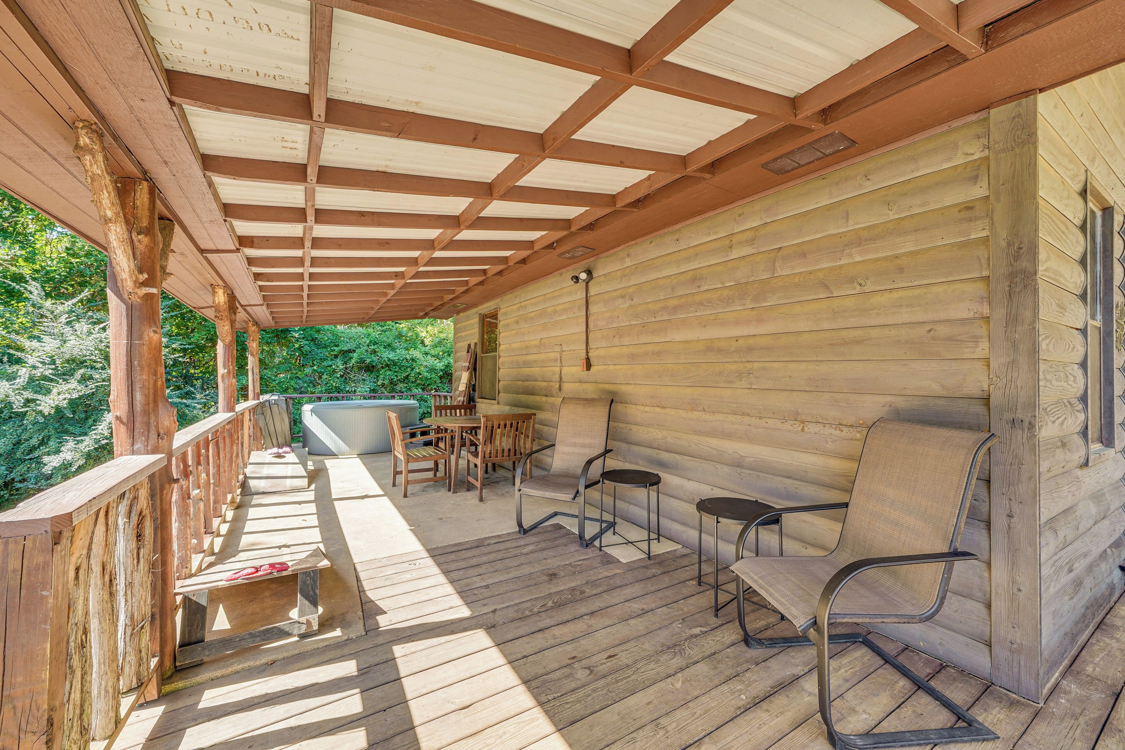 A wooden deck with a covered area, wooden chairs, and a table.