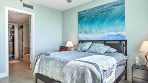 A bedroom with a bed, a nightstand, a wall-mounted painting, and a door leading to a bathroom. - South Padre Island Retreat w/ Beach Access! (South Padre Island)