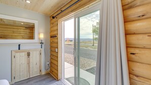 A wooden interior with a sliding glass door leading to an outdoor area, a built-in cabinet, and a small window. - Secluded Grand Junction Getaway w/ Sweeping Views! (Grand Junction)