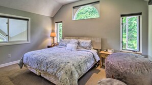 A bedroom with a large bed, two bedside tables, a nightstand, and a window with a view of trees. - Bartlett Condo w/ Mtn-view Deck < 1 Mi to Skiing! (Bartlett)