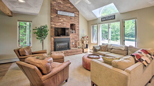 A spacious living room with leather sofas, a fireplace, and a large window offering a view of the mountains. - Bartlett Condo w/ Mtn-view Deck < 1 Mi to Skiing! (Bartlett)