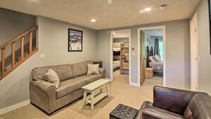 A living room with a sofa, a bench, and a leather chair. There is a staircase on the left and a door leading to another room. - Bartlett Condo w/ Mtn-view Deck < 1 Mi to Skiing! (Bartlett)
