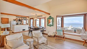 A spacious living room with a view of the sea, wooden beams on the ceiling, a dining area, and a kitchen with hanging pots. - Oceanfront Ferndale Oasis w/ Fire Pit, Grill! (Ferndale)