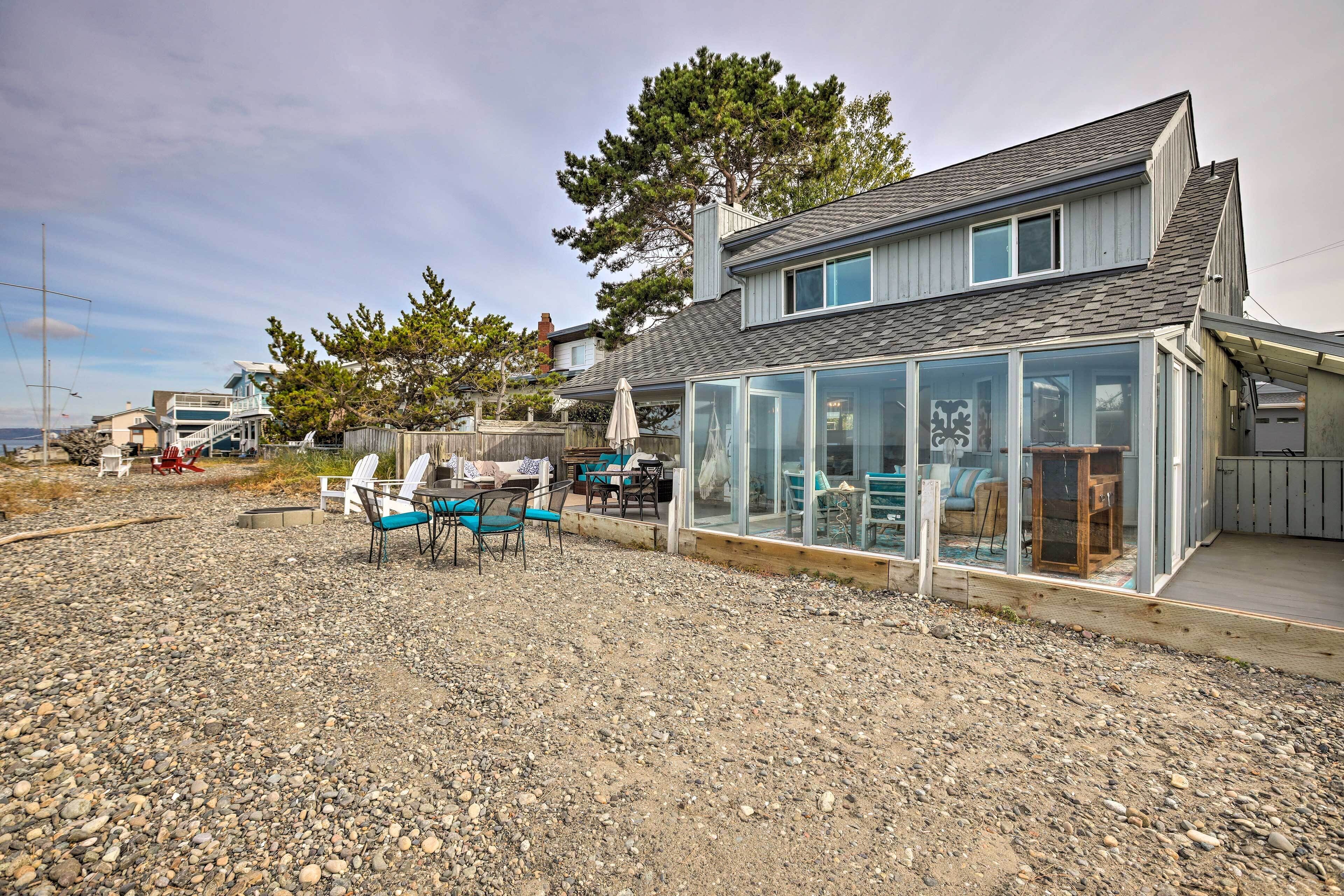 A modern house with a glass-enclosed patio area, outdoor furniture, and a view of the surrounding landscape.