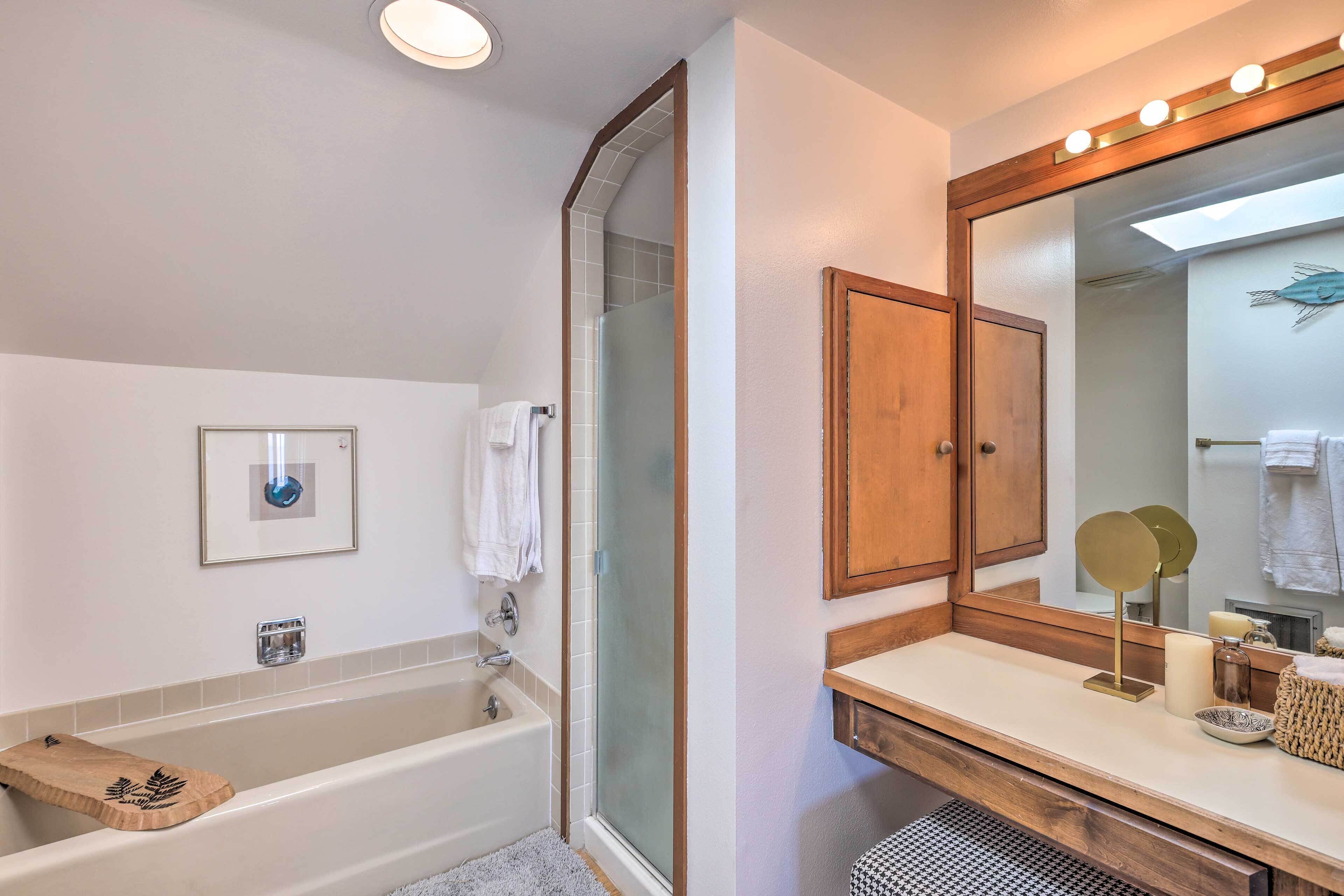 A bathroom with a bathtub, a shower, a vanity with a mirror, and a towel rack.