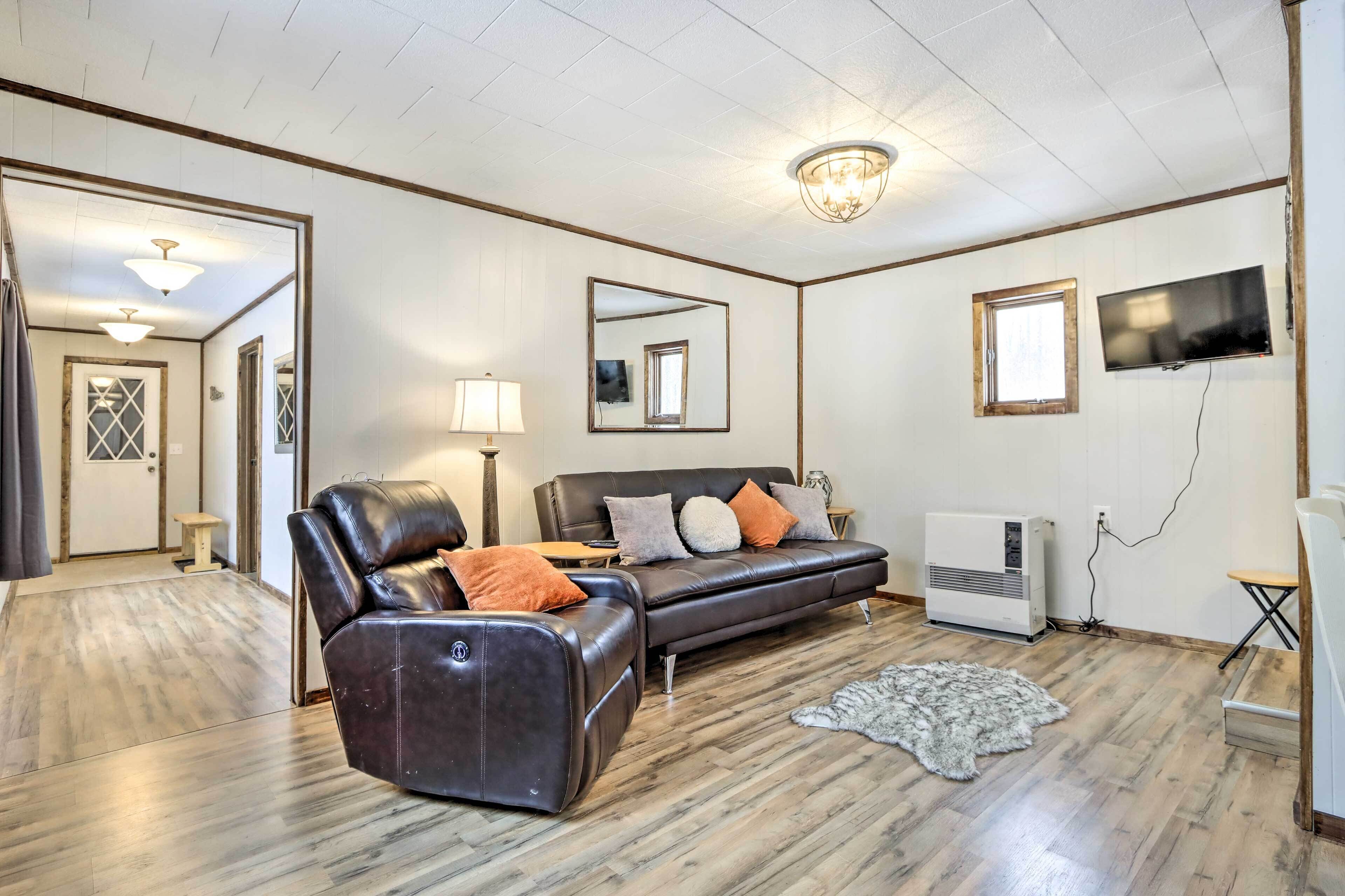 A living room with a leather sofa, a small table, a lamp, a TV, and a radiator.