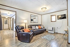 A living room with a leather sofa, a small table, a lamp, a TV, and a radiator. - Creekside Cabin < 2 Mi to Hike, Bike & Ski! (Palmer)