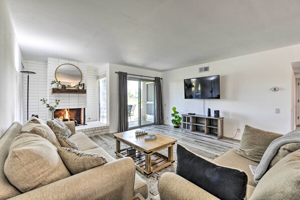 A modern living room with a fireplace, a large TV mounted on the wall, and a comfortable seating area with sofas and a coffee table.