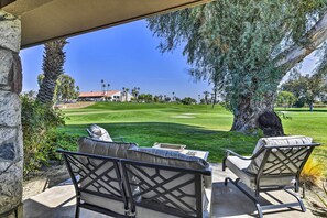 A patio with two chairs overlooking a golf course.
