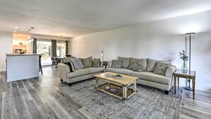 Ein modernes Wohnzimmer mit einem Ecksofa, einem Couchtisch und einer Küchenzeile im Hintergrund.