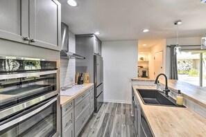 A modern kitchen with stainless steel appliances, a wooden countertop, and a built-in oven.