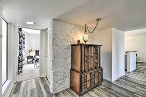 A hallway with a wooden cabinet, a patterned curtain, and a light fixture.