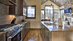 A modern kitchen with a large island, stainless steel appliances, and a stone accent wall.