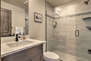 A modern bathroom with a glass-enclosed shower, a white sink with a dark faucet, and a toilet. - Ideally Located Winter Park Townhouse w/ Hot Tub! (Winter Park)