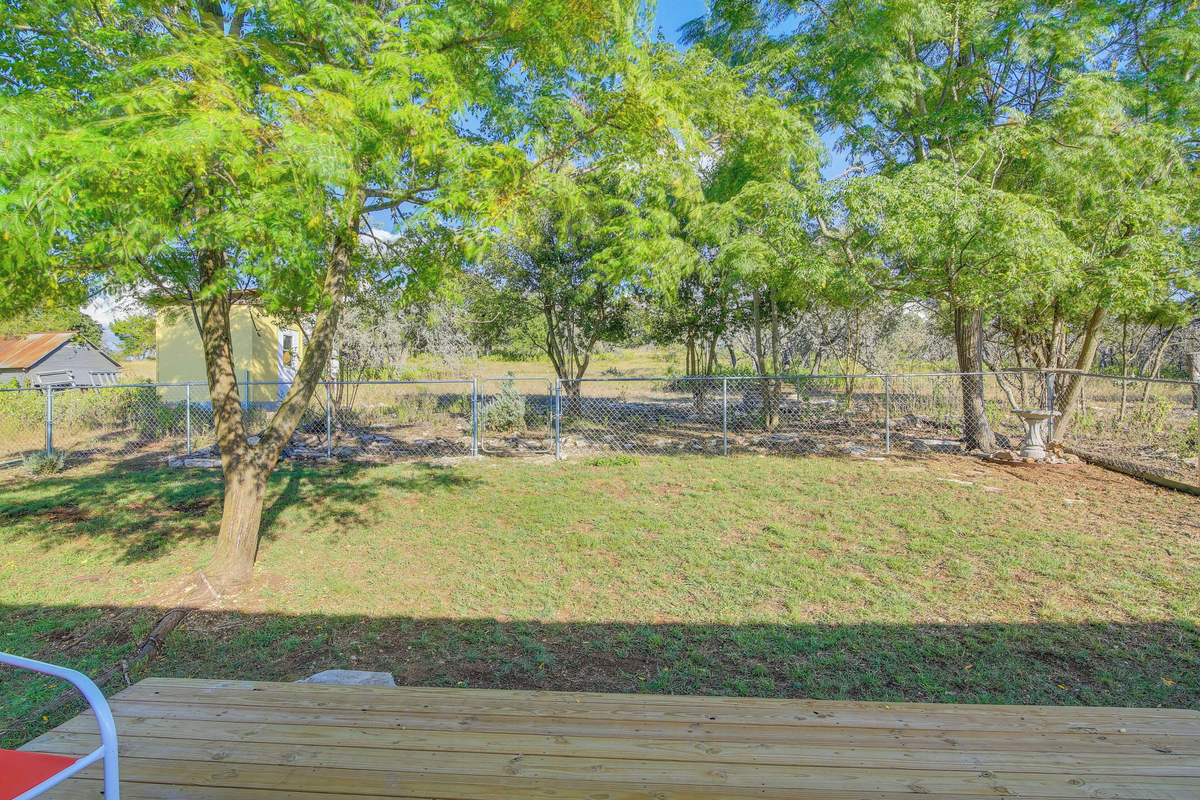 A fenced outdoor area with trees and a wooden deck.