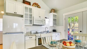 A kitchen with white cabinets, a microwave, and a dining table set with plates, bowls, and glasses. - Ranch Cabin w/ Decks, 10 Mi to Fredericksburg (Fredericksburg)