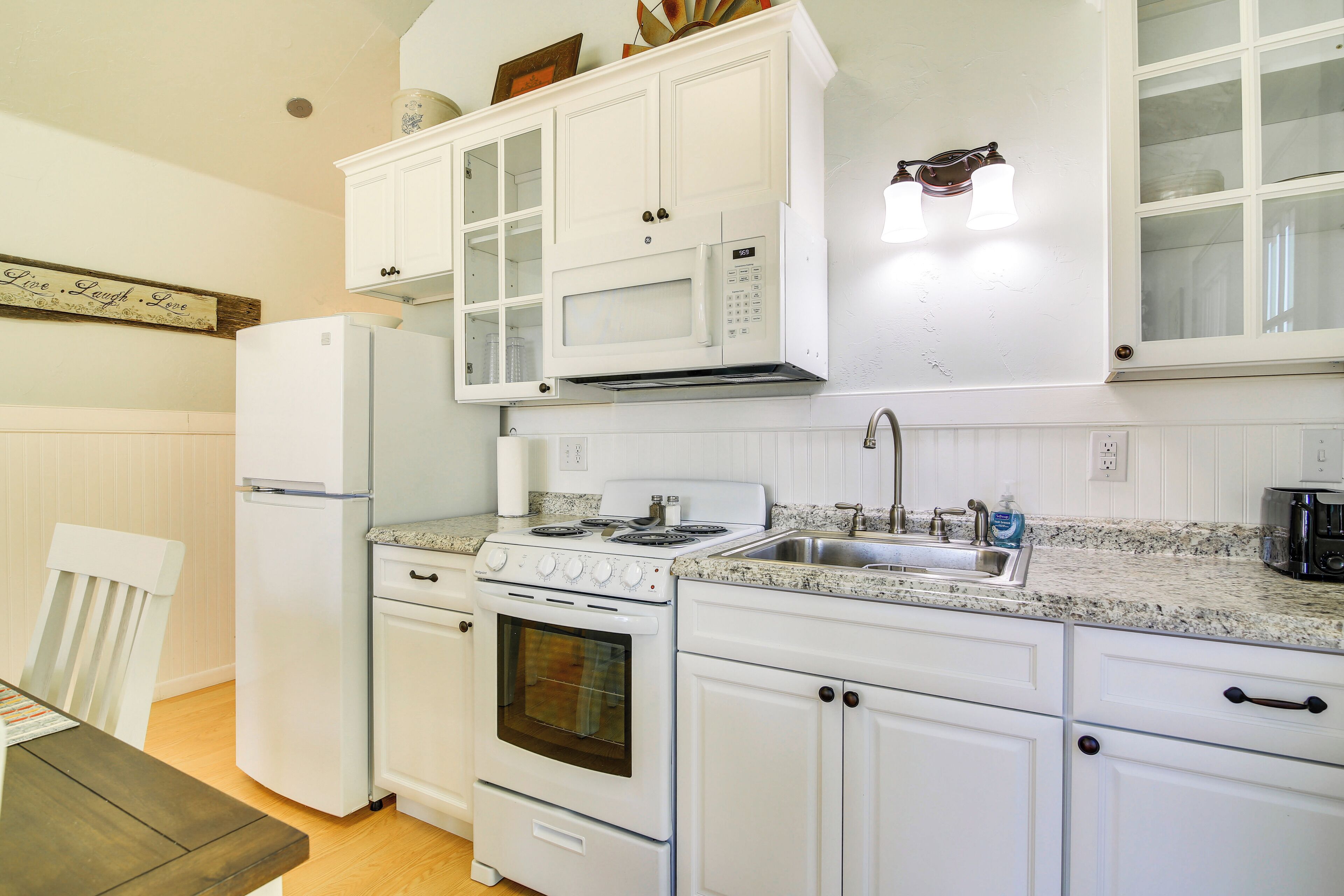 A kitchen with white cabinets, a refrigerator, a stove, and a microwave.