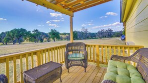 A wooden deck with wicker furniture and a view of a grassy field and trees. - Ranch Cabin w/ Decks, 10 Mi to Fredericksburg (Fredericksburg)