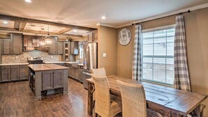 A spacious kitchen with dark wood cabinets, a central island, and a dining area with wicker chairs. - Waterfront Louisiana Vacation Rental w/ Dock! (Many)