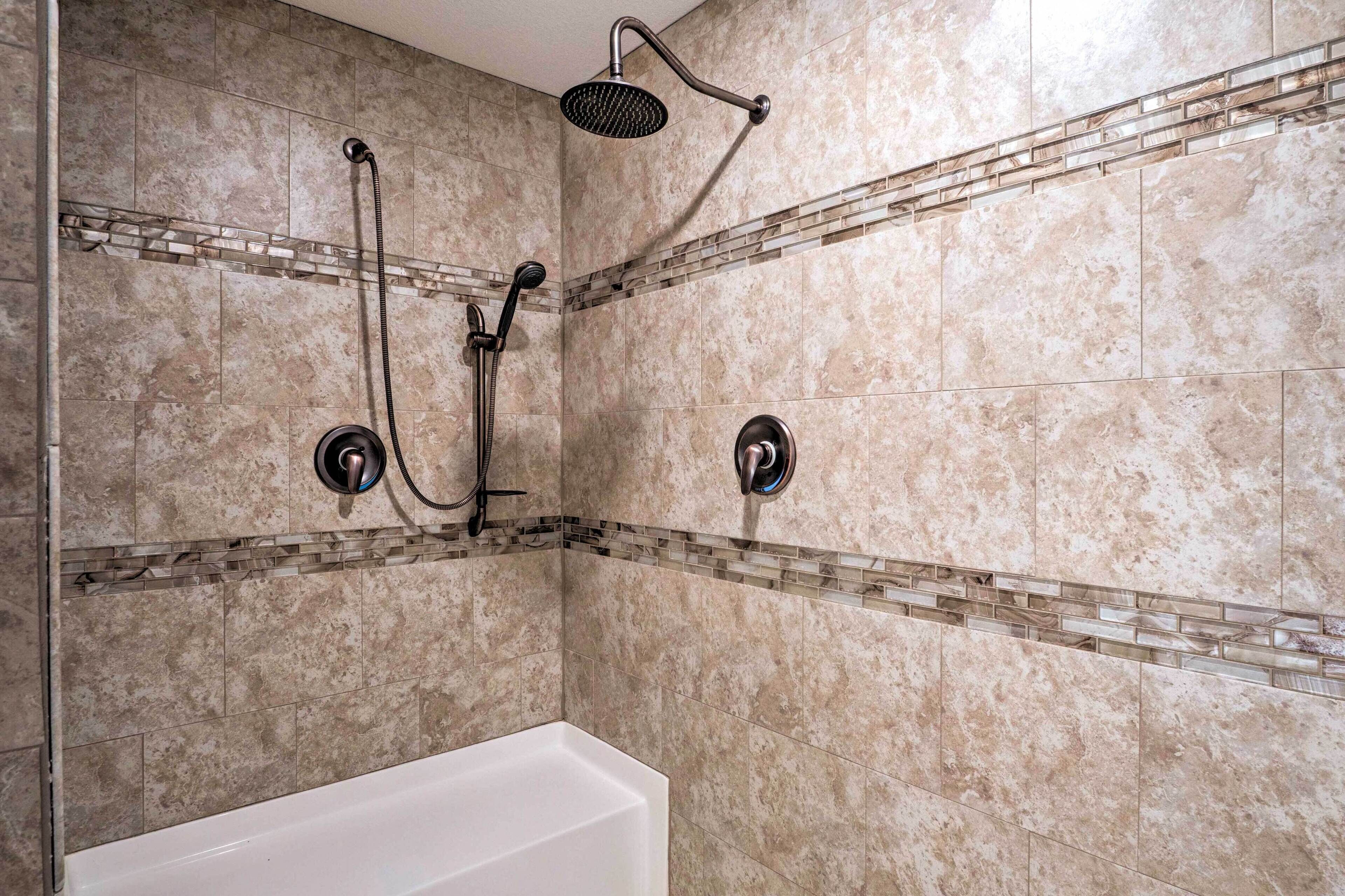 A bathroom with a shower, two faucets, and a bathtub.